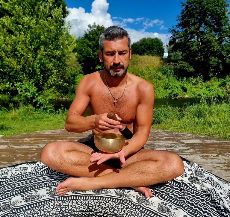 A man is sitting in a yoga pose with a bowl